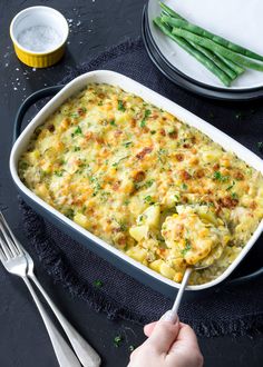 a casserole dish with potatoes and green beans in it on a black surface