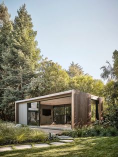 a small house in the middle of some trees and grass with a walkway leading to it