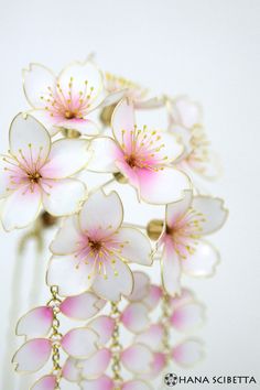 pink and white flowers are hanging from a hair comb