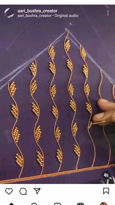 someone is stitching gold thread on a purple background