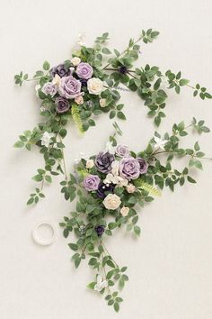 two bouquets of flowers and greenery on a white surface with a pair of scissors