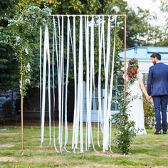 a bride and groom are standing in front of an outdoor ceremony arch decorated with white streamers