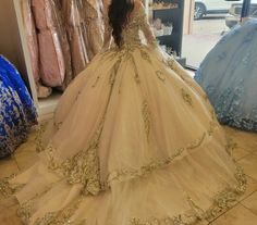 a woman in a ball gown looking at herself in the mirror with gold sequins on it