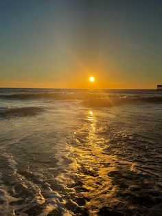 the sun is setting over the ocean with waves