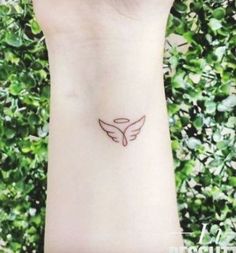 a small tattoo on the wrist of a woman's left arm with an angel wing