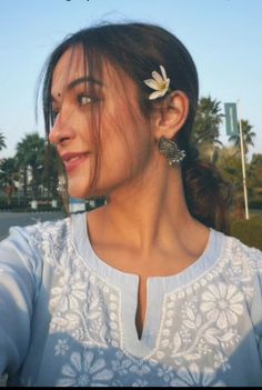 a woman with a flower in her hair is looking off into the distance and smiling