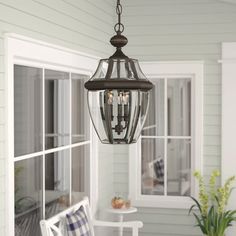 a light fixture hanging from the ceiling in front of a porch with chairs and table