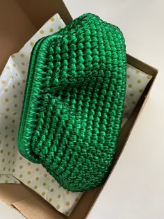 a green basket sitting inside of a box on top of a white and yellow polka dot paper