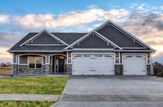 a large house with two garages in the front yard and grass on the side