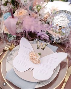 a table set with plates, napkins and place settings for an elegant butterfly themed wedding