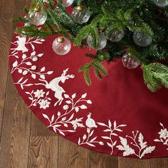 a christmas tree skirt on the floor with baubles hanging from it's branches