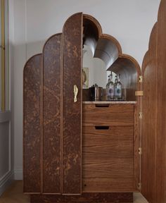 a wooden cabinet sitting in the corner of a room next to a mirror and door