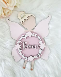 a pink angel ornament sitting on top of a white furnish with flowers