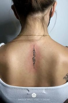 the back of a woman's neck with a tattoo on her left upper arm