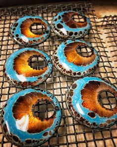 four blue and brown donuts sitting on top of a cooling rack