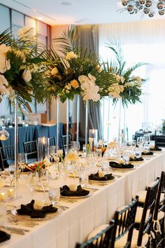 a long table is set up with white flowers and black place settings for an event