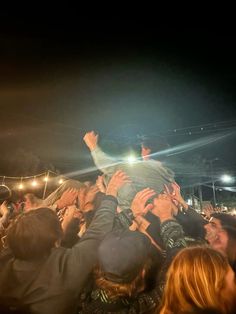 a group of people standing around each other with their hands in the air at a concert