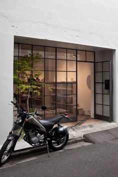 a motorcycle is parked in front of a building with glass doors on the outside wall