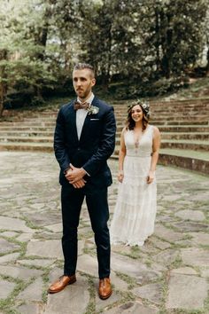 a man in a suit and bow tie standing next to a woman in a white dress