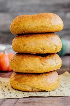 a stack of three bagels sitting on top of a piece of paper next to some tomatoes