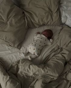 a baby is sleeping on a bed with white sheets