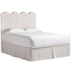 the bed is made with white linens and has a scalloped headboard