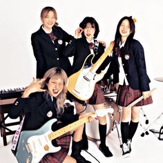 three girls in school uniforms are posing with guitars and guitar strings while one girl is on the phone