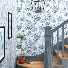 a blue and white floral wallpaper in a hallway with stairs leading up to the second floor