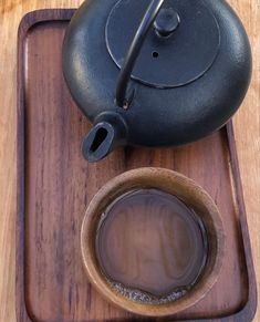 a teapot and cup sitting on a wooden tray next to each other with liquid in it