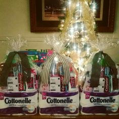 three bags of cottonelle wrapped in plastic sitting next to a christmas tree