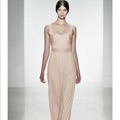 a woman walking down a runway wearing a nude colored dress with sheer shoulders and straps