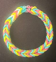 a bracelet made out of multicolored braiding on a black surface with a silver clasp