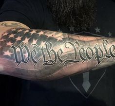 a man with a large arm tattoo that says we the people