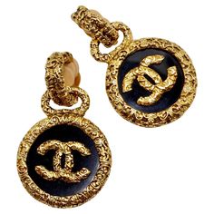 Introducing the exquisite Chanel 1993 Gold Tone Black CC Medallion Florentine Earrings, a stunning pair that exudes timeless elegance and sophistication. Crafted with meticulous attention to detail, these earrings are sure to elevate any ensemble with their unique design and impeccable craftsmanship. The earrings feature textured gold-plated discs adorned with black enamel charms, each embellished with a striking gold-plated CC logo at its center. This iconic Chanel motif adds a touch of luxury and glamour to the design, making these earrings a true statement piece. With their clip-on style, these earrings are both comfortable to wear and easy to style. The textured gold finish adds a unique and eye-catching touch that sets them apart from the rest of your collection, ensuring you stand ou Luxury Chic Black Enamel Jewelry, Luxury Gold Engraved Earrings, Luxury Engraved Gold Earrings, Luxury Gold Clip-on Earrings, Luxury Polished Clip-on Earrings For Formal Occasions, Luxury Engraved Earrings For Anniversary, Designer Engraved Evening Jewelry, Luxury Yellow Gold Earrings, Designer Engraved Jewelry For Evening