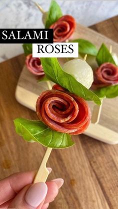 someone is holding up a flower made out of bacon and spinach on a skewer