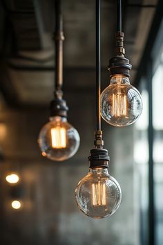 three light bulbs hanging from the ceiling in an industrial style room with exposed lighting fixtures