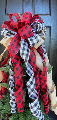 a red and black bow on top of a christmas tree in front of a door