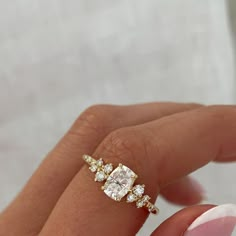 a woman's hand holding an engagement ring with three diamonds on top of it