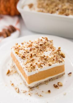 a piece of cake sitting on top of a white plate next to a bowl of nuts