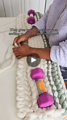 a woman is working on an item with purple dumbbells in front of her