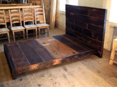 a wooden bed frame sitting on top of a hard wood floor next to a window