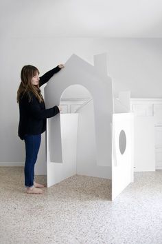 a woman standing in front of a white house shaped like a castle with its door open