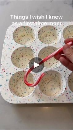 someone is using scissors to cut out cupcakes in a muffin pan with sprinkles