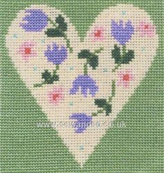 a cross stitch heart with purple flowers on the inside and green grass in the background