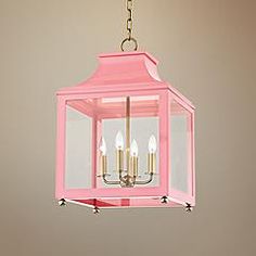 a pink lantern hanging from a ceiling fixture with four candles in it and one light on the other side