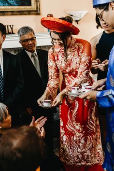 a woman in a red hat is serving tea to other people at a wedding reception