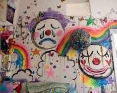 there is a colorful wall with clowns and rainbows painted all over the walls