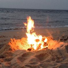 a fire pit on the beach with water in the background