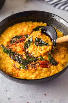 a bowl filled with lentil and spinach next to a spoon on top of it