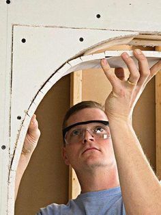 a man in glasses is holding up a piece of wood